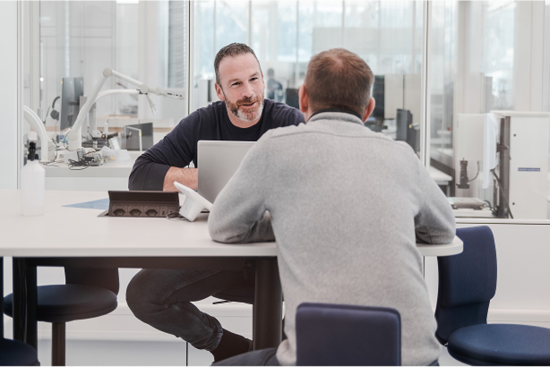 Deux collaborateurs assis dans un environnement de production moderne ayant une conversation amicale.
